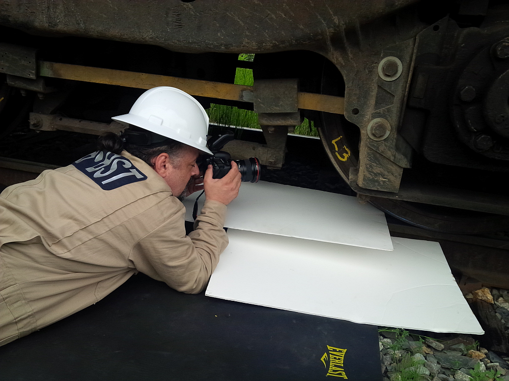 Tony Gasbarro, spécialiste des services multimédias pour les enquêtes, prend des photos d'un essieu monté sur une locomotive à Lac-Mégantic